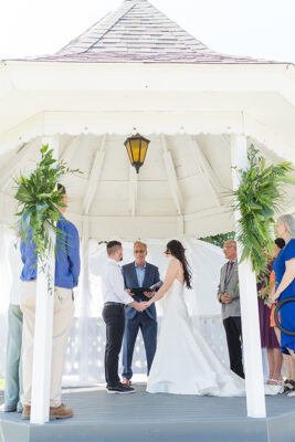 Bride and groom standing in gazebo in front of pastor