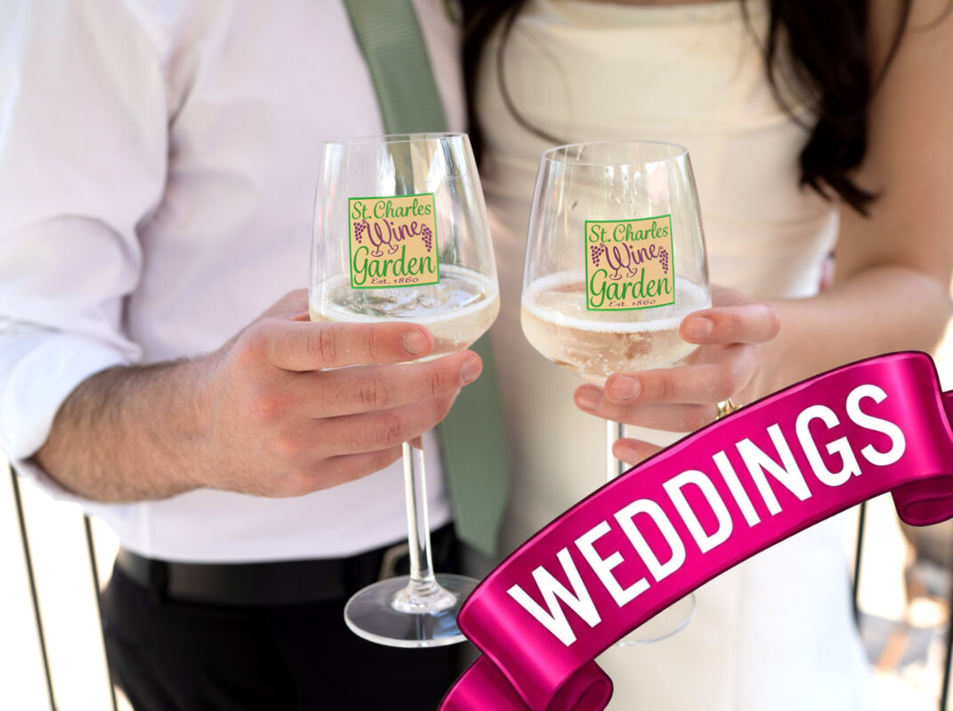 Close-up of a wedding couple toasting with two glasses of white wine. The glasses are printed with a green and purple logo for "St. Charles Wine Garden." A vibrant magenta ribbon banner with the word "WEDDINGS" in white capital letters is overlaid diagonally across the bottom right corner.